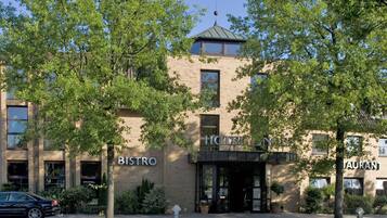 A hotel with a bistro and restaurant on the ground floor, surrounded by trees.