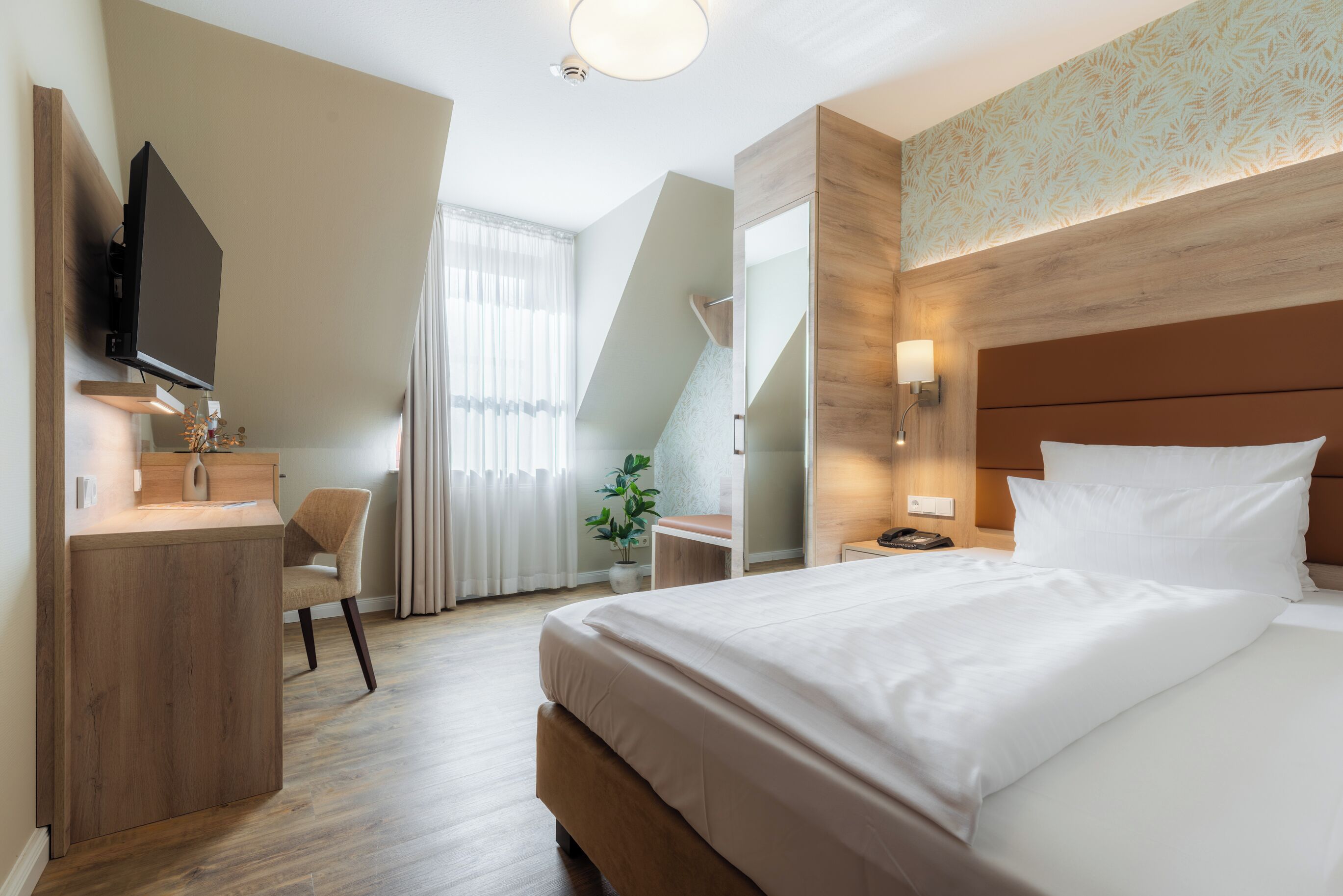 Une chambre d’hôtel avec un lit, un bureau, une chaise, une télévision et un escalier.