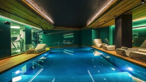 An indoor swimming pool with a wooden ceiling, mirrored walls, and lounge chairs along the sides. - Lasagrada Hotel Istanbul (Istanbul)