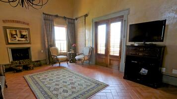 Una sala de estar con chimenea, dos sillones, un televisor y un tapete grande.