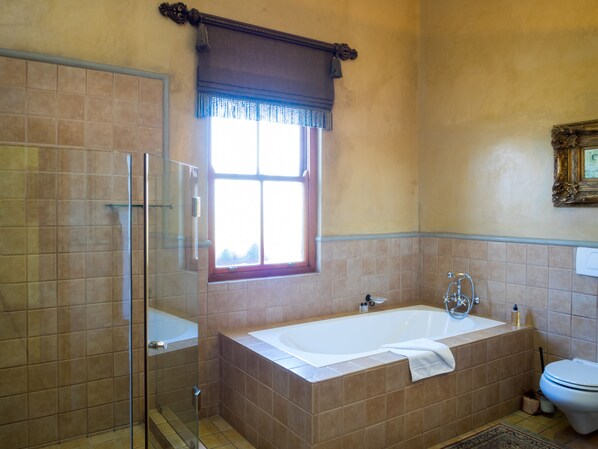 Un baño con cabina de ducha de vidrio, bañera y retrete.