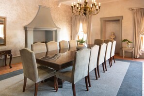 A formal dining room with a long table, multiple chairs, a chandelier, and a bust on the wall. - Castello di Monte (Pretoria)