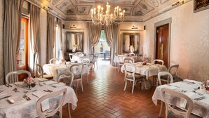 A dining area with multiple tables set for service, a chandelier, and classical ceiling artwork. - Castello di Monte (Pretoria)
