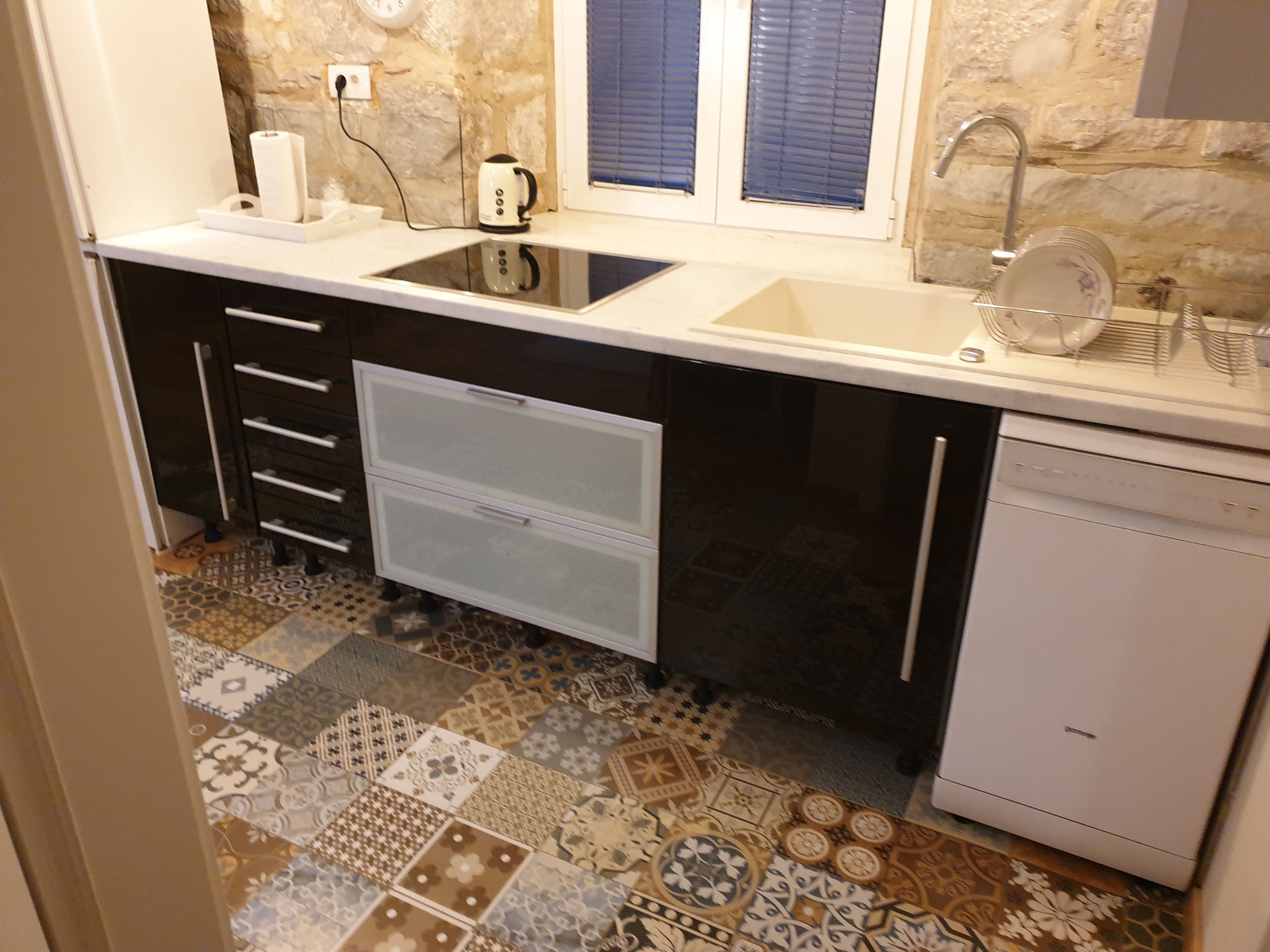 Una cocina compacta con un lavabo blanco, horno empotrado y lavavajillas.