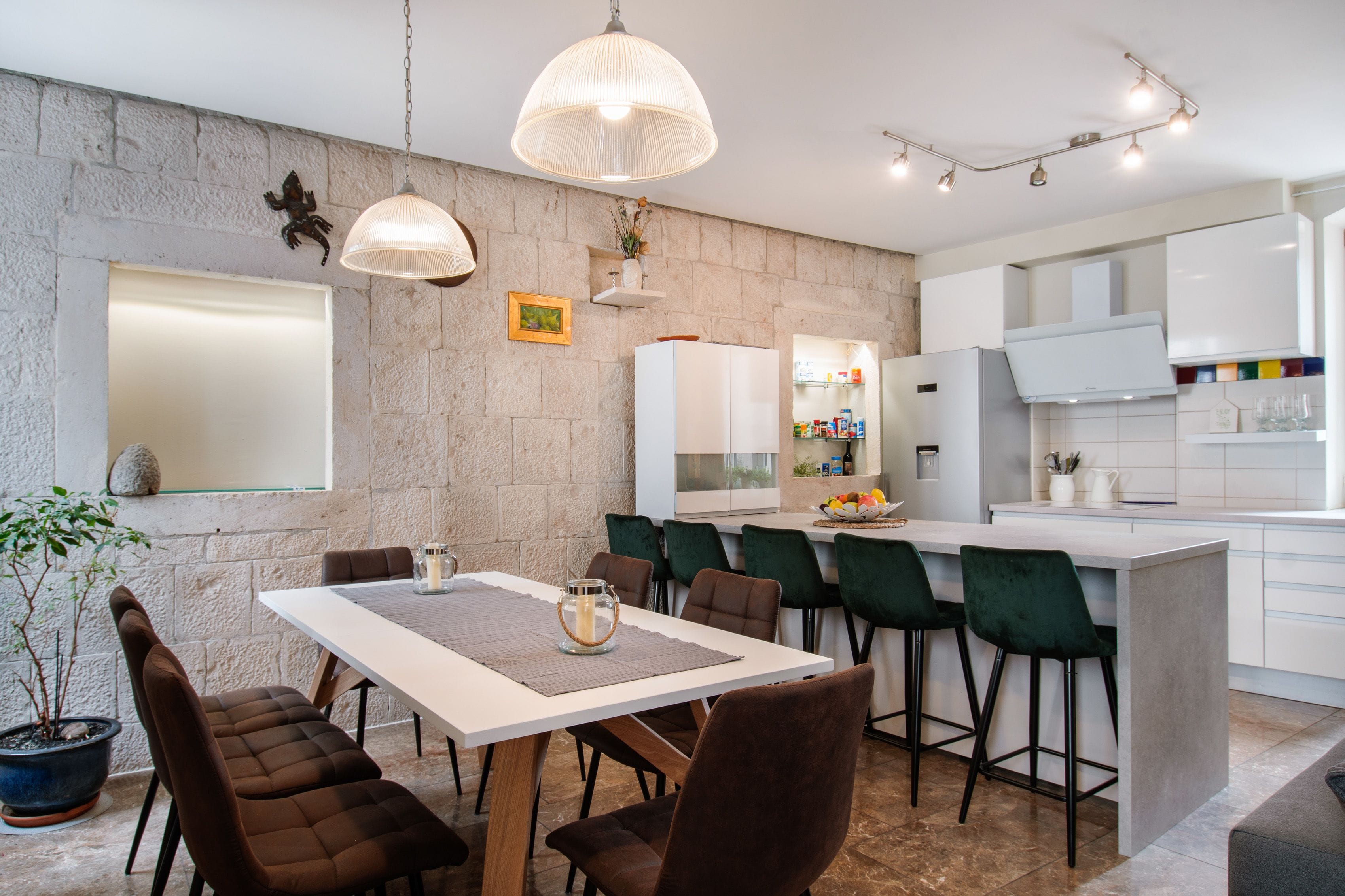 A modern kitchen with white cabinets, a central island, and a dining area with a table and chairs.
