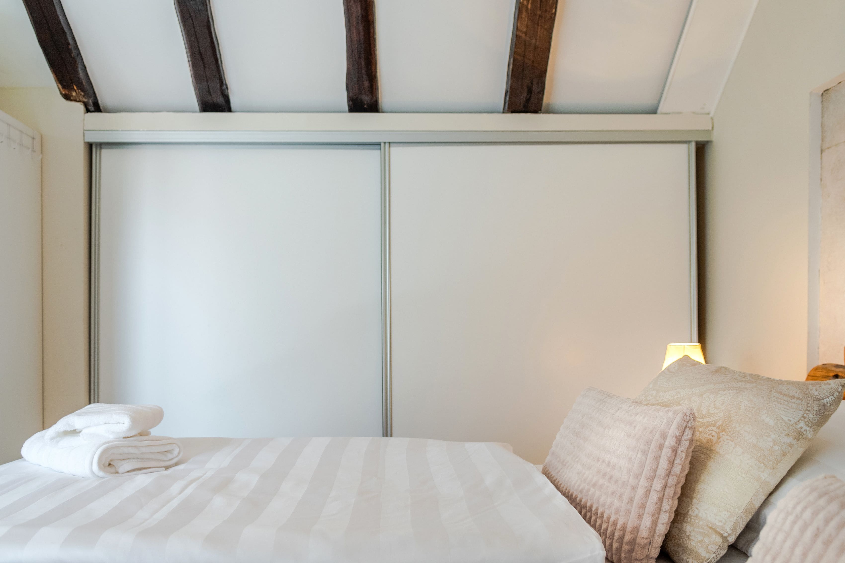 A neatly made bed with a striped bedspread, a folded towel, and two decorative pillows.