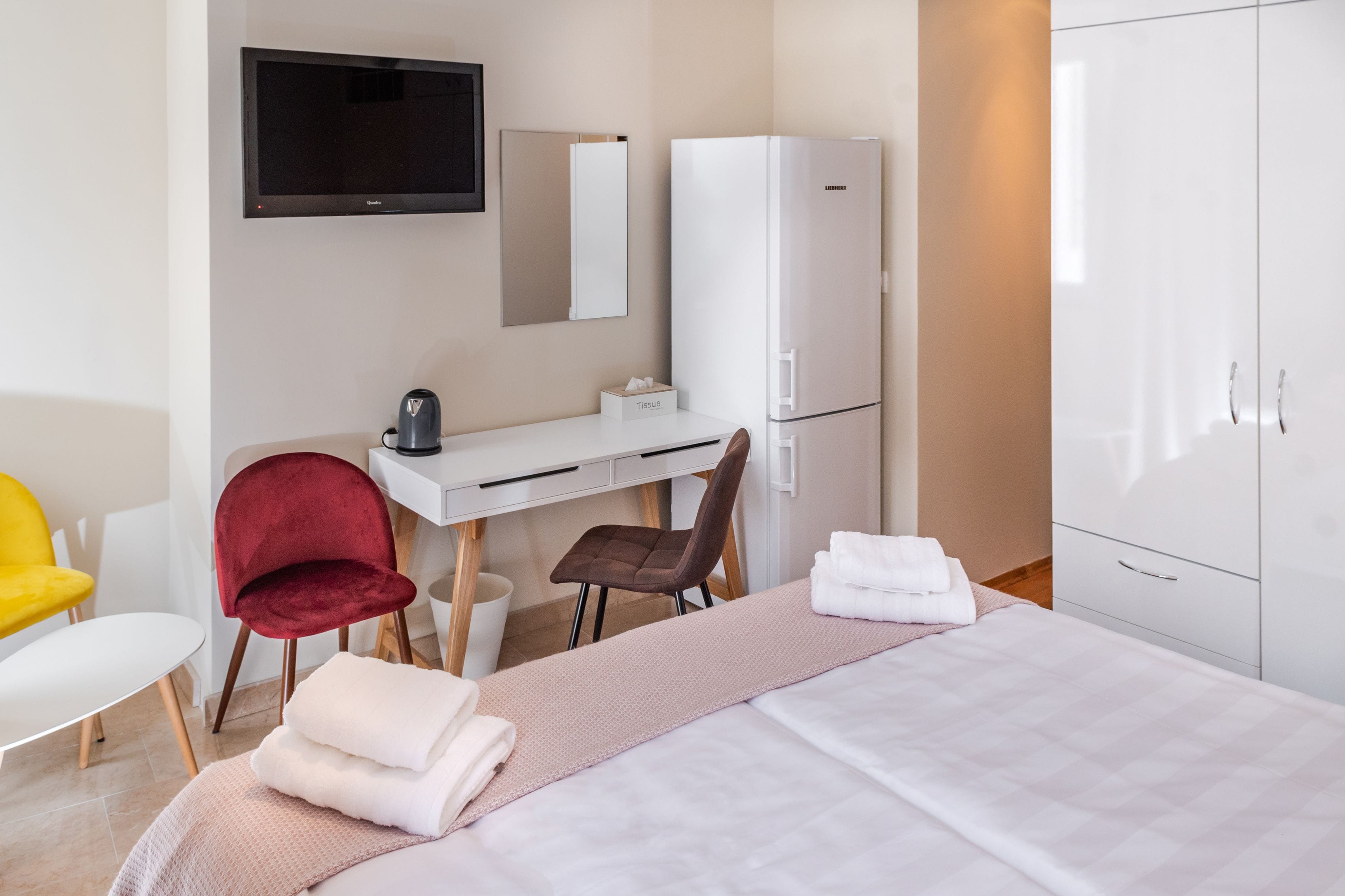 A hotel room with a bed, a desk, a chair, a television, and a wardrobe.