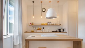 A modern kitchen with a wooden island, pendant lights, and a clock on the wall. - Bouganvillea Split Apartments (Split)