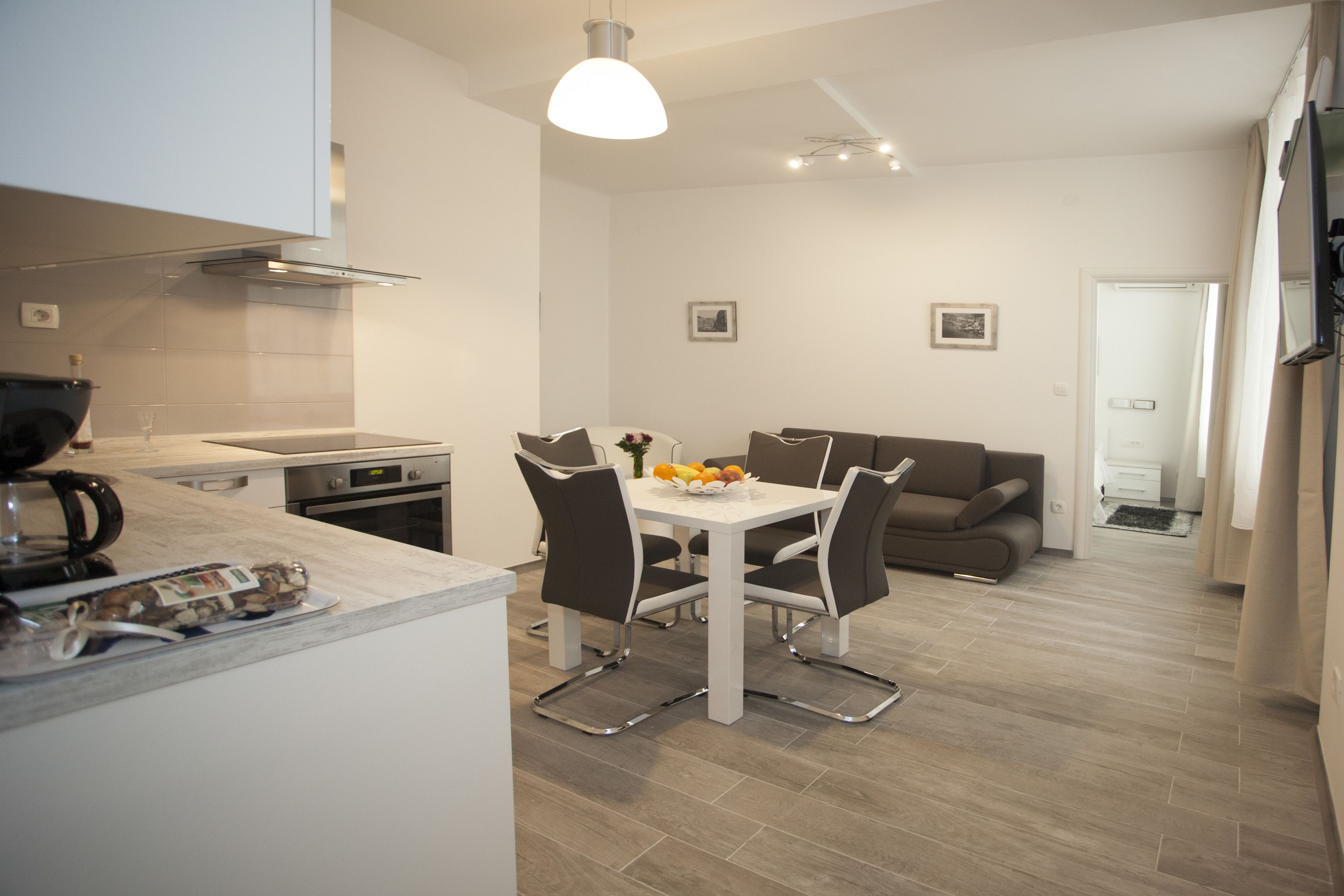 A modern kitchen with a dining area, a sofa, and a TV.