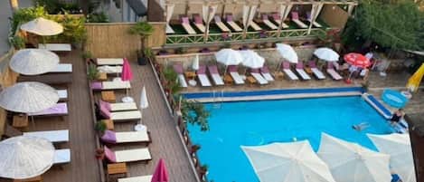 Alberca al aire libre, sombrillas en la alberca y camastros