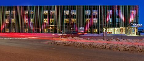 A modern building with vertical lines and illuminated windows at night.