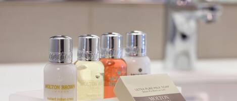 A bathroom with a white sink and four bottles of Molton Brown products.