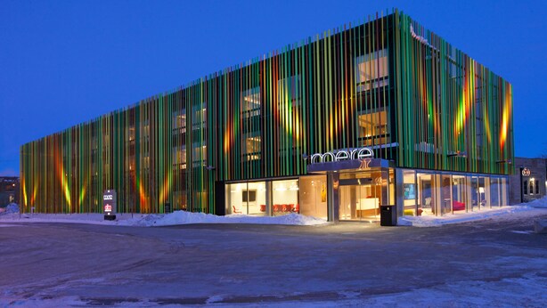 A modern building with vertical slats and glass windows, featuring a 'mere' sign. - Mere Hotel (Winnipeg)