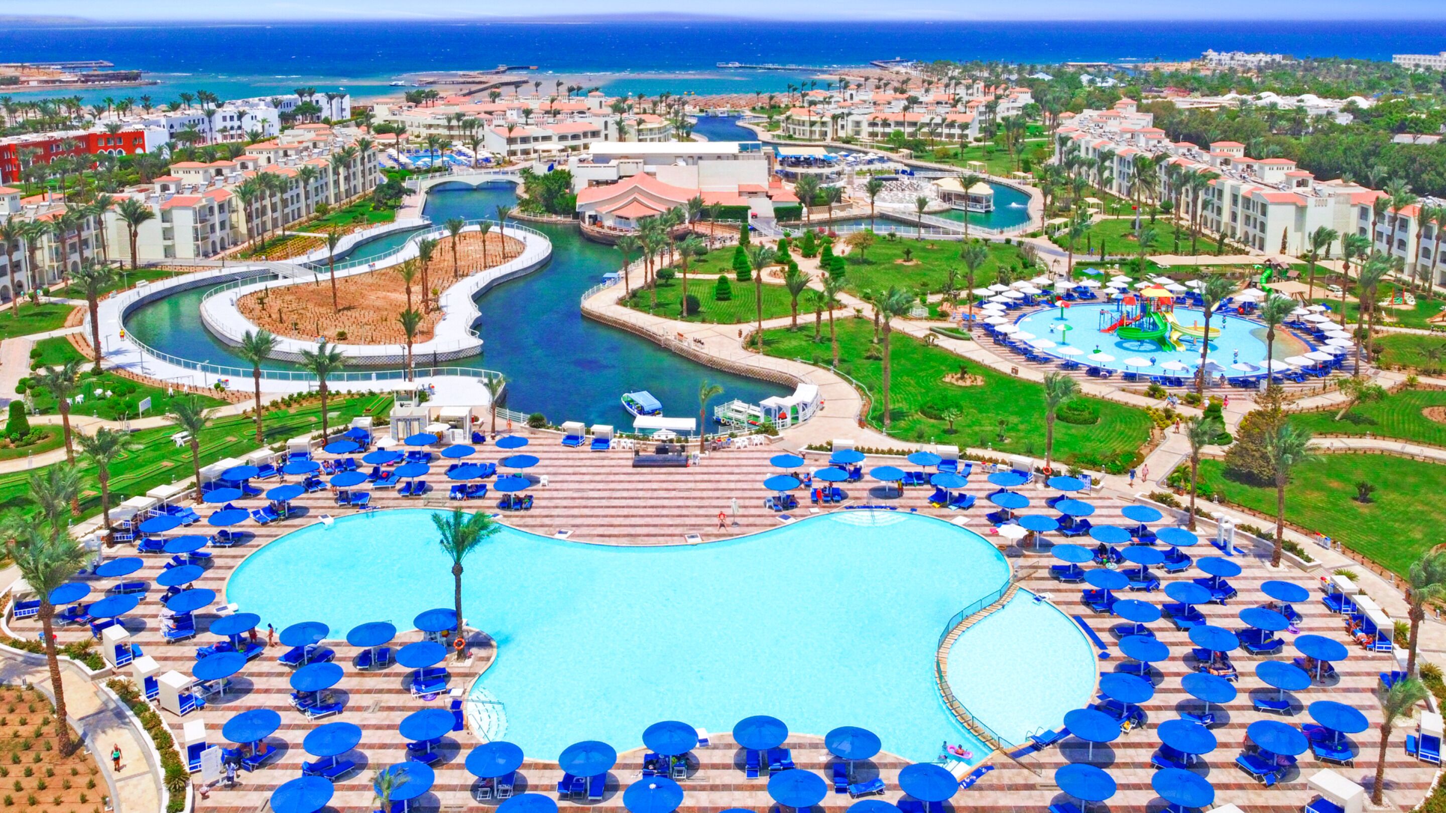 A resort with a large central pool, multiple smaller pools, and a variety of outdoor seating areas.