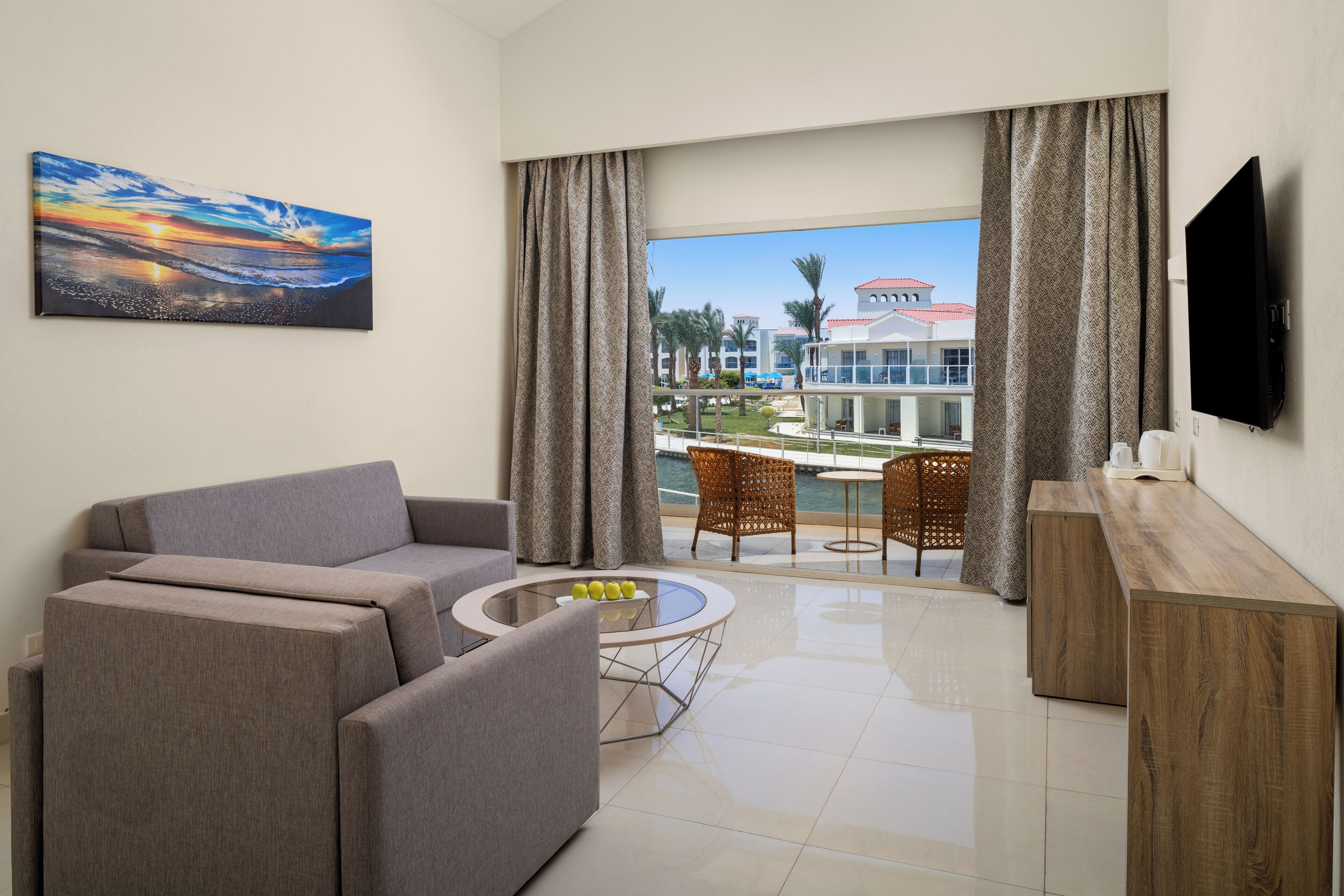 A modern hotel room with a sofa, a coffee table, and a TV.