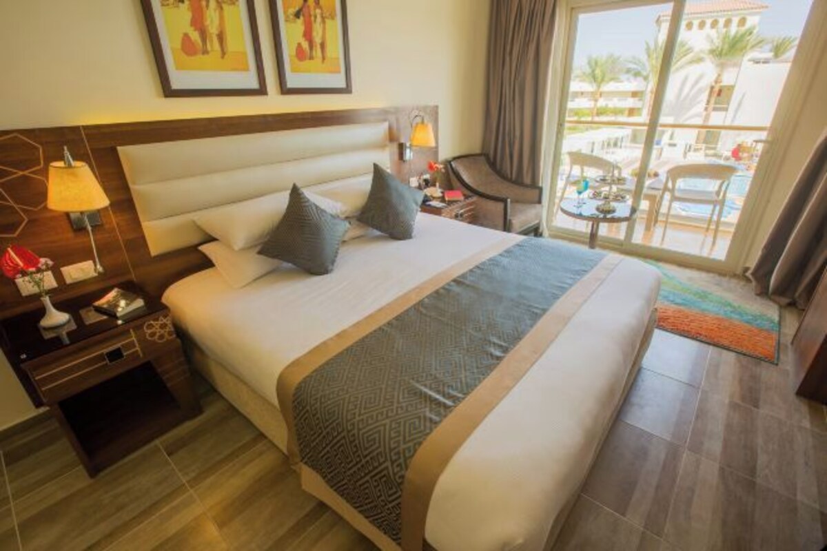 Una camera d'hotel con un letto grande, un comodino, una scrivania, una sedia e vista sull'esterno.
