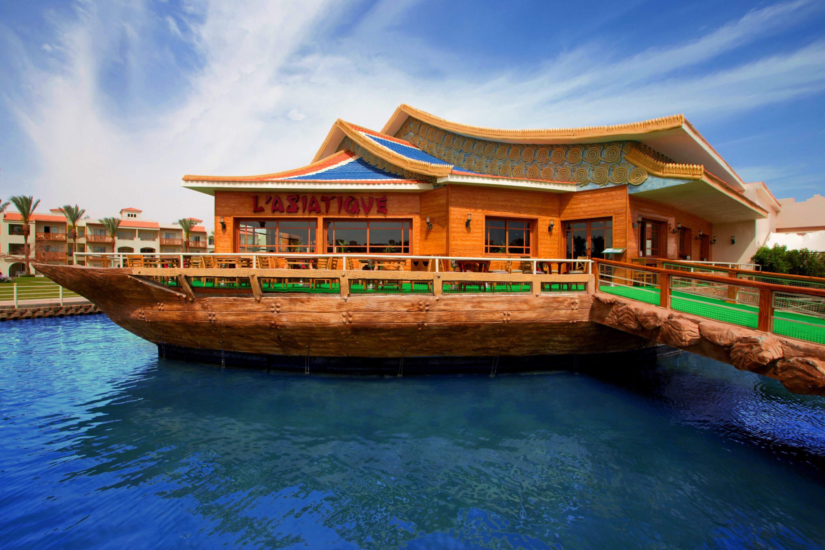 A building with a traditional architectural style, featuring a wooden boat-shaped structure over a pool.
