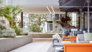 An outdoor seating area with modern furniture, a large umbrella, and decorative plants.