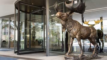 A modern building entrance with a glass door and a bronze moose sculpture in front.