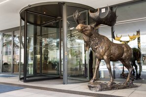 A modern building entrance with a glass door and a bronze moose sculpture in front. - Scandic Frankfurt Museumsufer (Frankfurt)