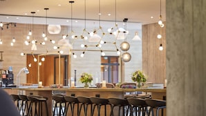 A modern bar area with multiple hanging light fixtures, bar stools, and decorative plants.