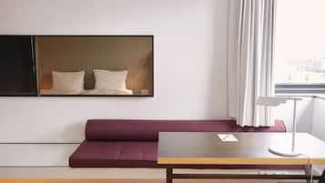 Ein modernes Hotelzimmer mit Holzboden, einer Couch, einem Tisch, einer Lampe und einem großen Spiegel an der Wand.
