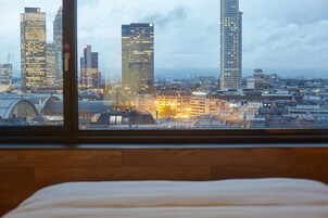 Vista sulla città da una stanza con pavimento in legno e un letto in primo piano.