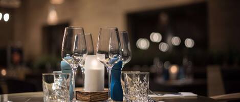 A dining table set with multiple wine glasses, a white candle, and a blue vase.