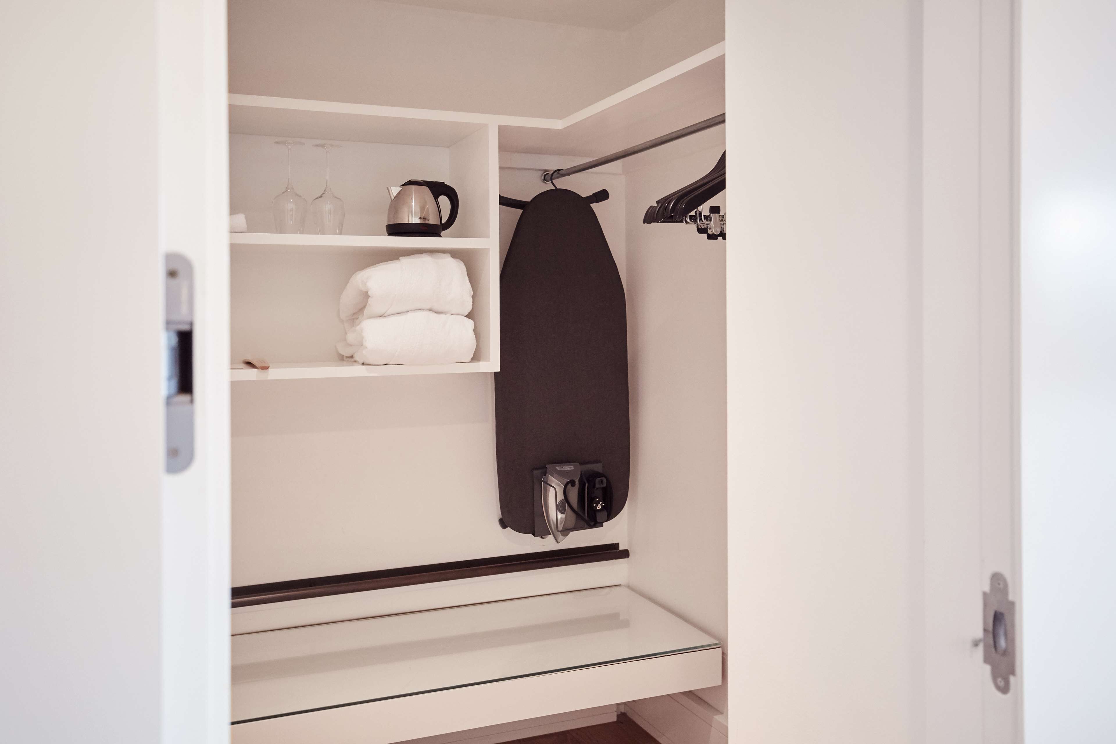Un baño moderno y compacto con estante empotrado para artículos de tocador, toallero y zona de ducha.