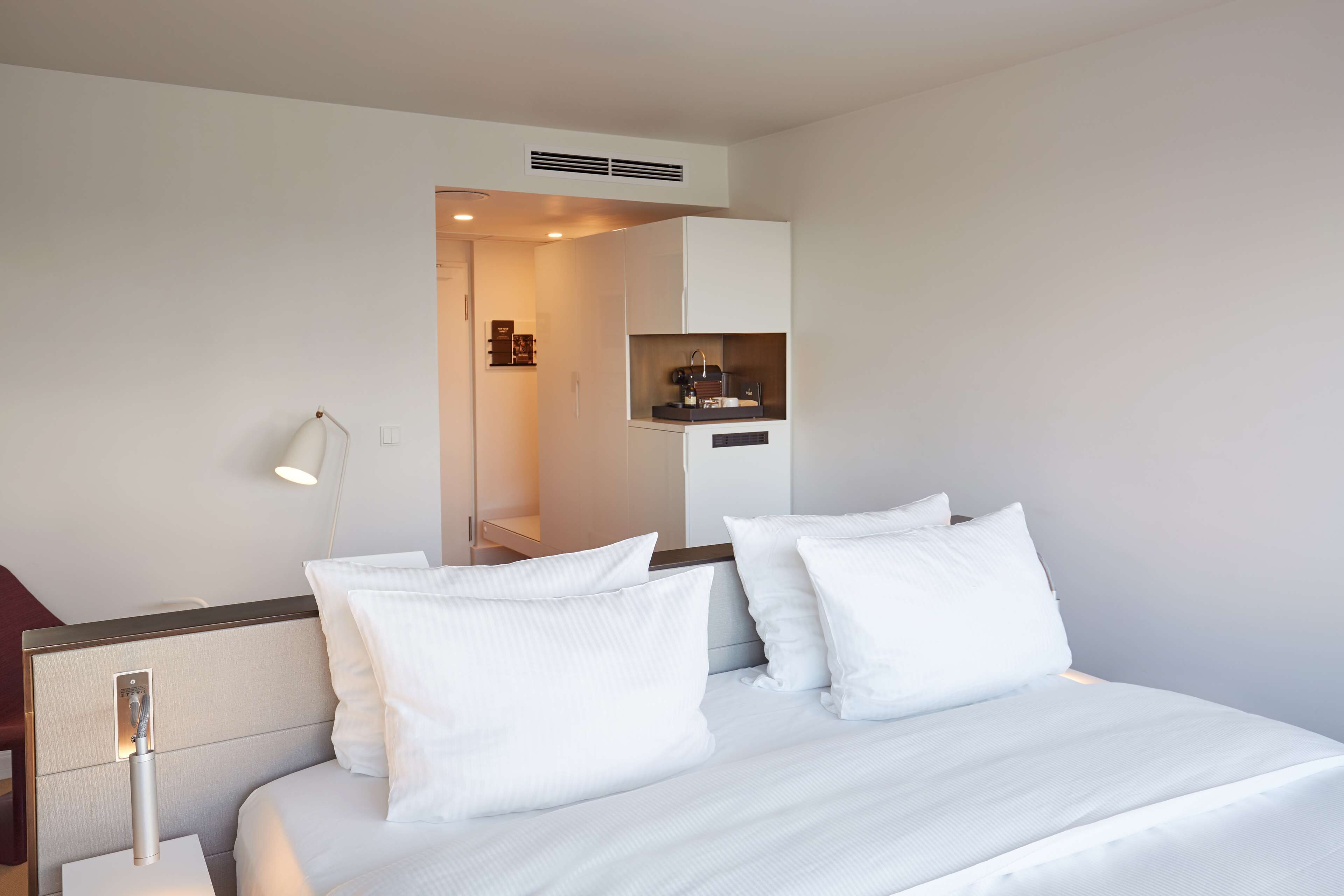 Une chambre d’hôtel avec un lit bien fait, une lampe de chevet et un petit coin cuisine.