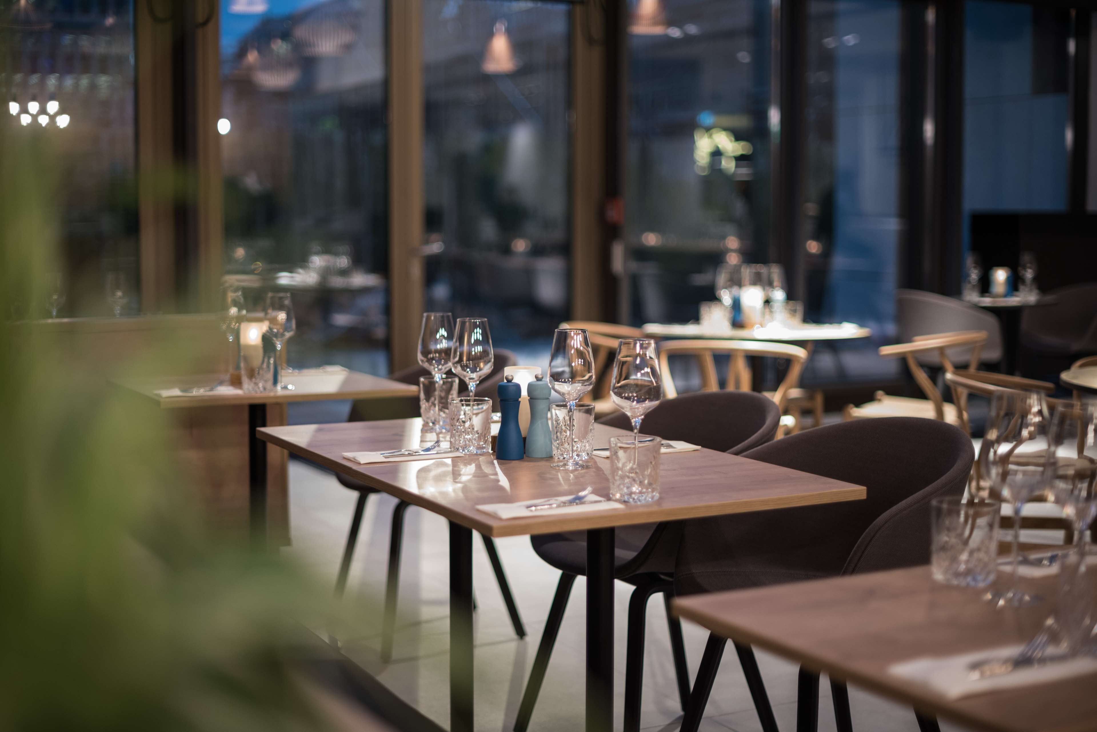A restaurant with tables set for dining, featuring clear glassware and a modern interior design.
