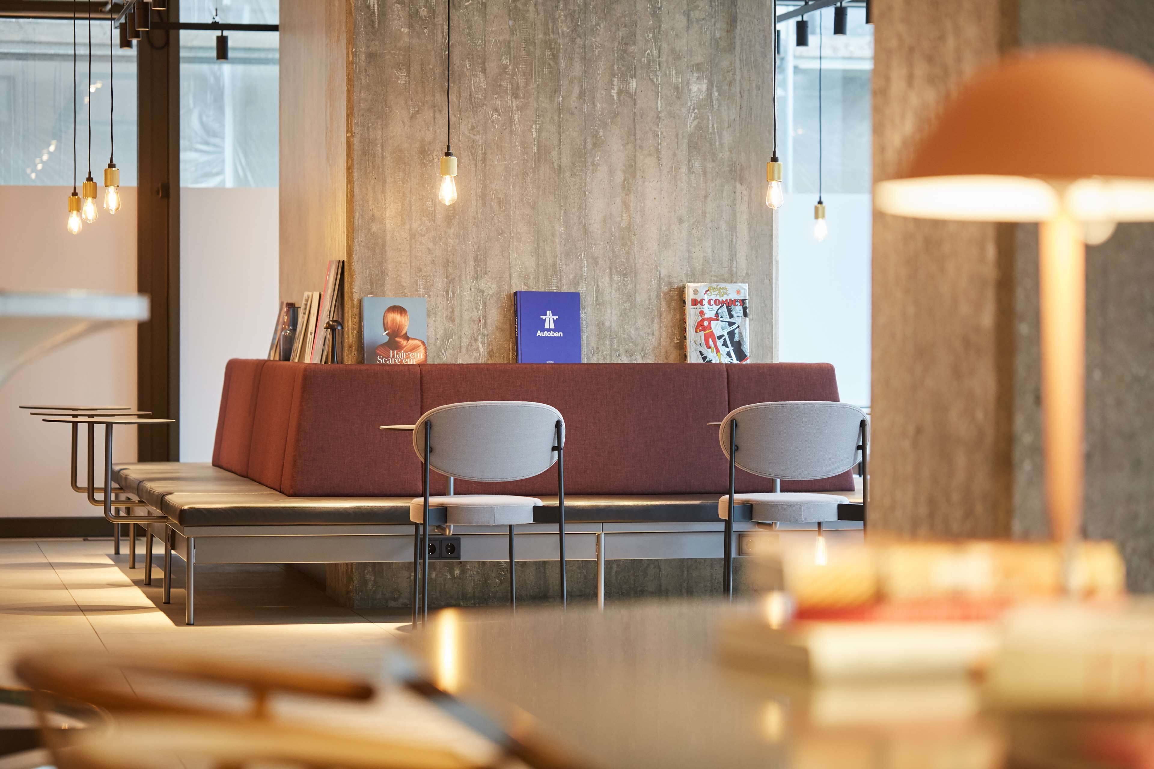 A modern waiting area with a reception desk, chairs, and bookshelves.