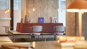 A modern waiting area with a reception desk, chairs, and bookshelves.