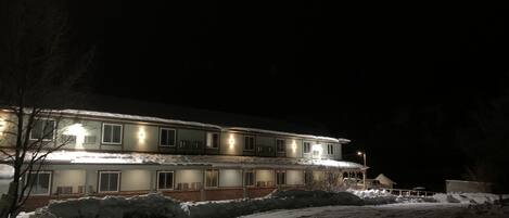 Ein mehrstöckiges Hotel mit beleuchteten Fenstern und verschneitem Gelände.