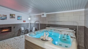 A modern spa room with a hot tub, a fireplace, and a seating area. - RiverWalk Inn (Pagosa Springs)