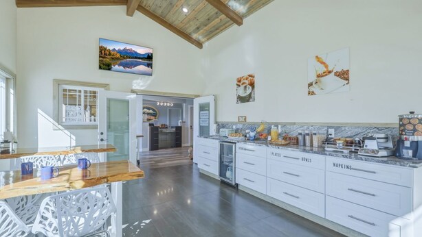A spacious kitchen with a wooden ceiling, a dining area with chairs, and a view of a mountain landscape through a window. - RiverWalk Inn (Pagosa Springs)