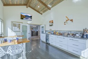 Une cuisine spacieuse avec un plafond en bois, un coin repas avec des chaises et une vue sur un paysage montagneux par une fenêtre.