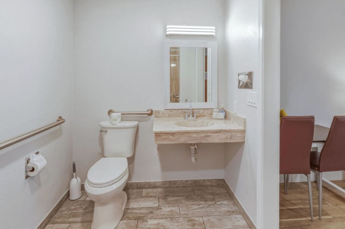 A small bathroom with a toilet, sink, and mirror.