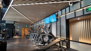Ett modernt gym med löpband, träningsutrustning och ett träpanelat tak.