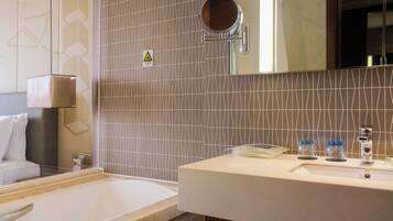 Ein Badezimmer mit einer Badewanne, einem Waschbecken mit Spiegel und einem Handtuchhalter.