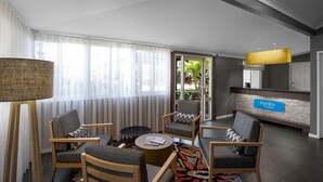 Un moderno vestíbulo de hotel con zona de estar, una recepción y vistas al exterior.