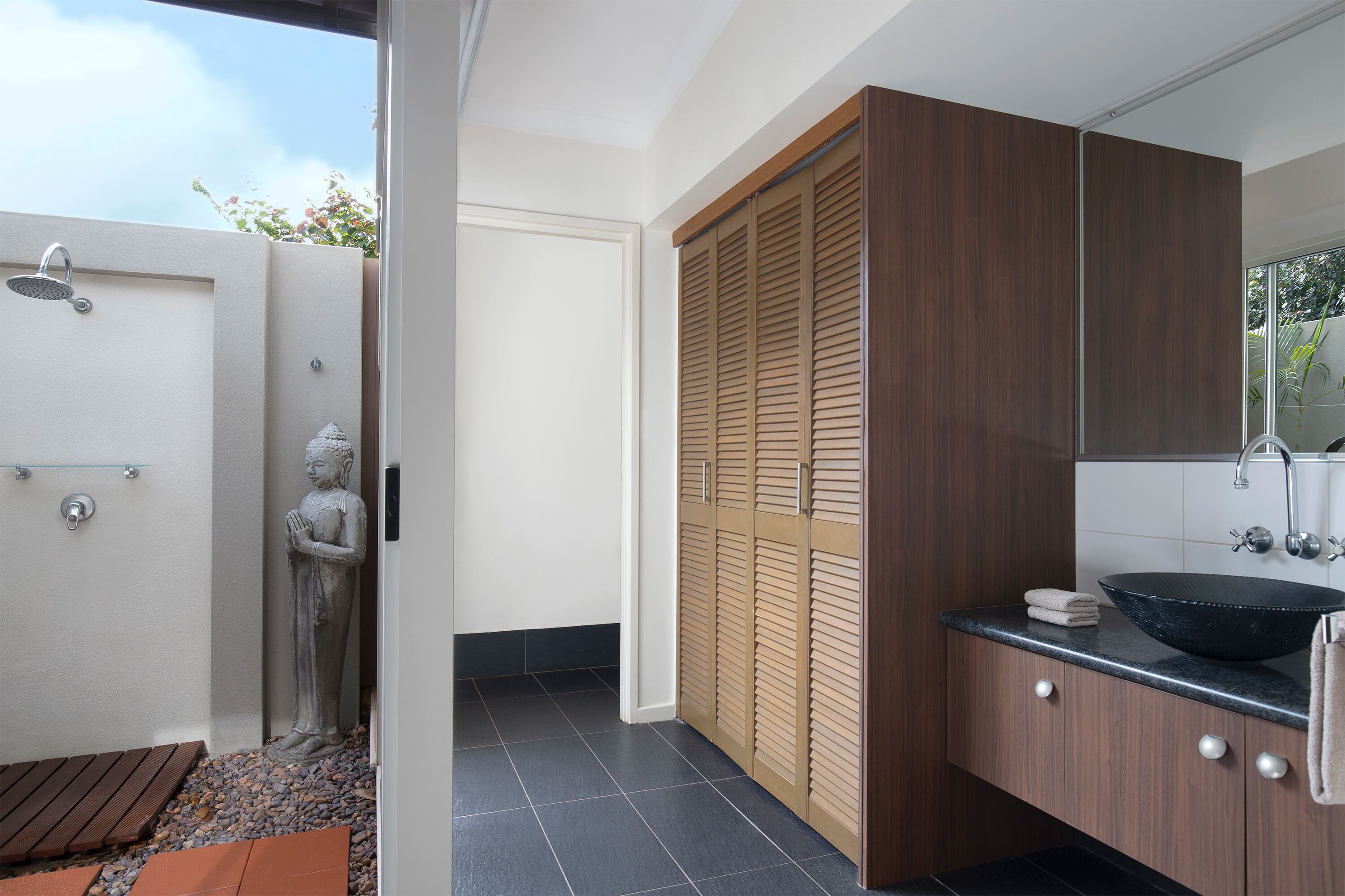 A modern bathroom with a shower, a basin, and a wooden wardrobe.