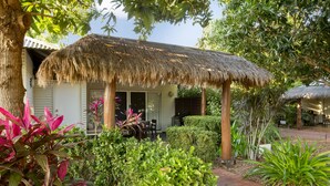 Una estructura con techo de paja y un patio, rodeada de plantas y árboles.