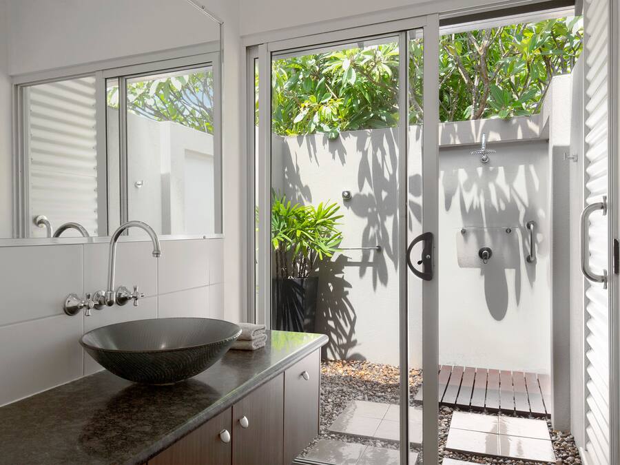 Un baño moderno con un lavamanos grande, un espejo y una zona de ducha con puerta de vidrio.