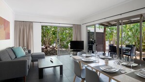 Una sala moderna con un sofá, una mesita de centro y una zona de comedor preparada para cuatro.