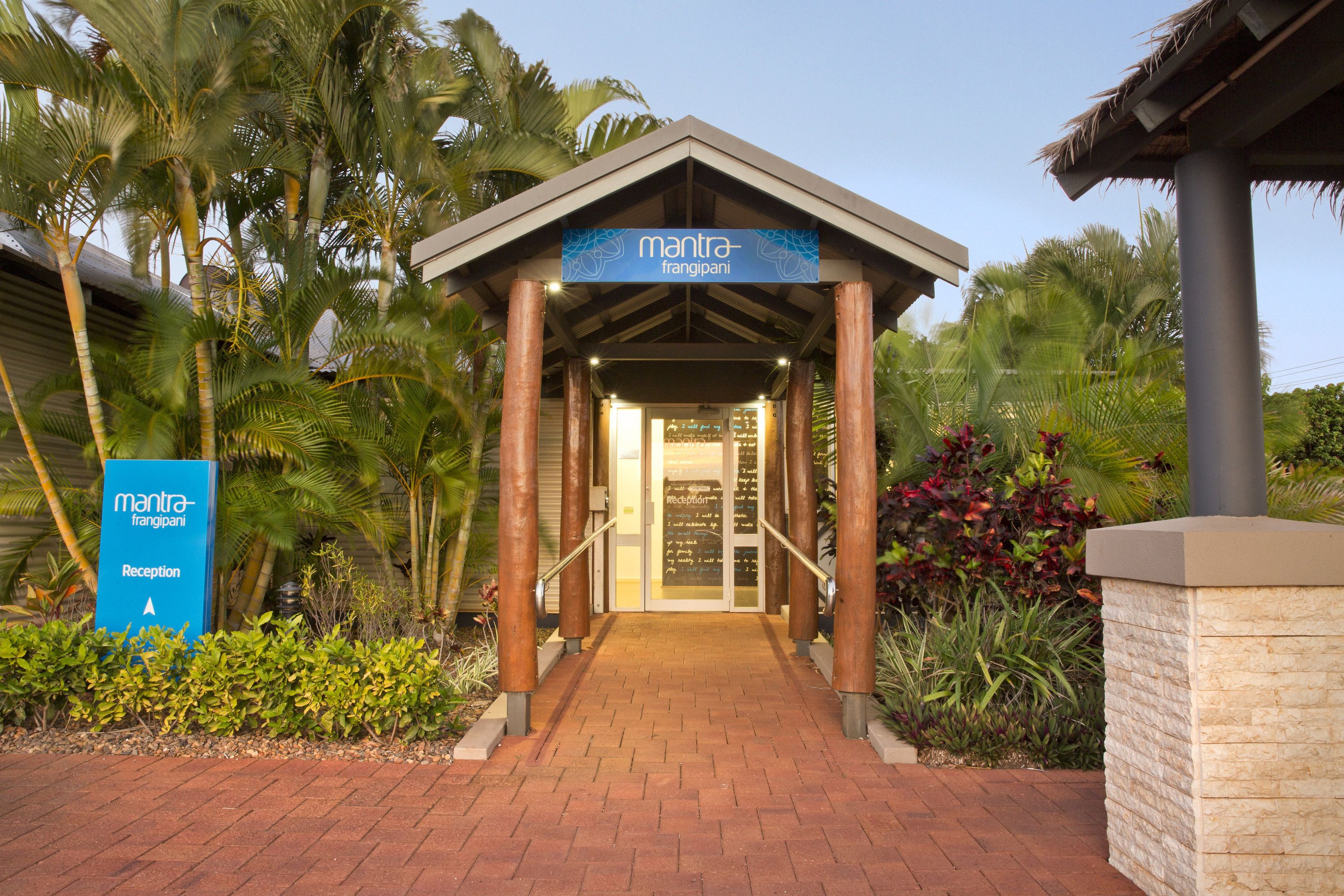 A reception area with a sign for 'mantra-frangipani' leading to a building entrance.