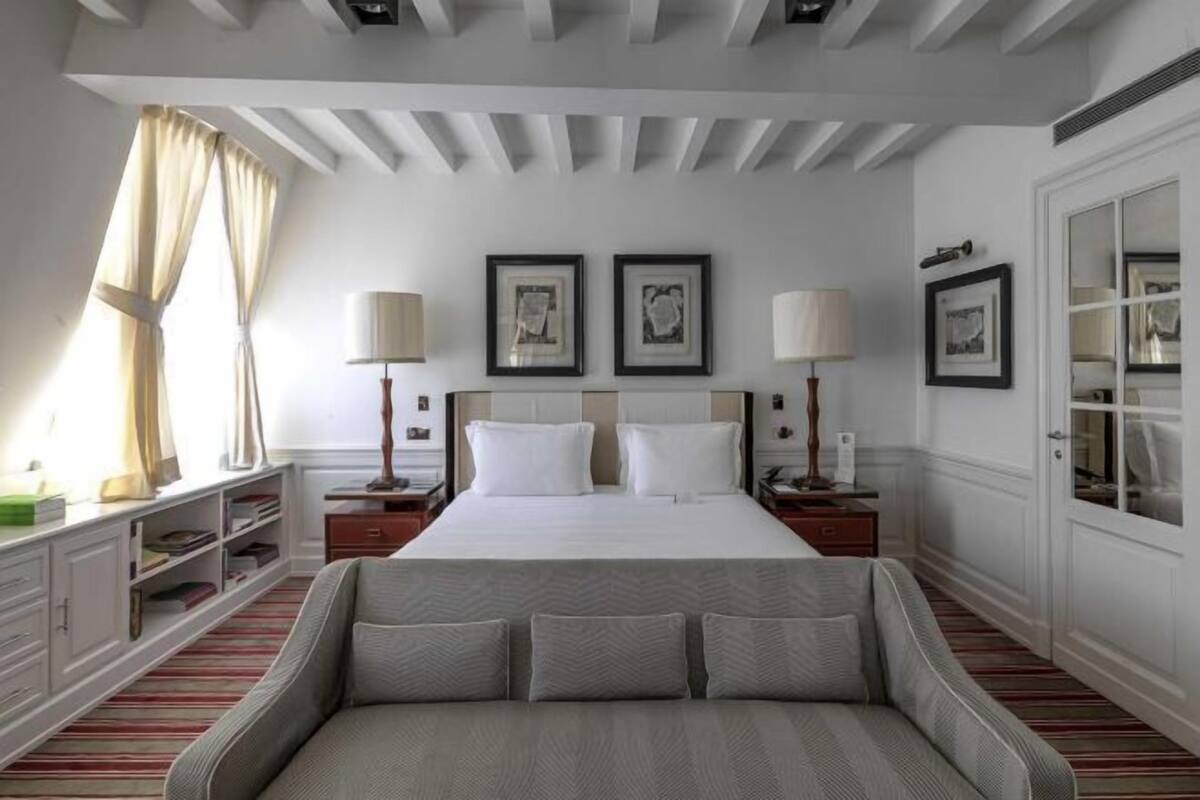 Une chambre à coucher avec un grand lit, deux tables de chevet, un canapé et une fenêtre avec des rideaux.