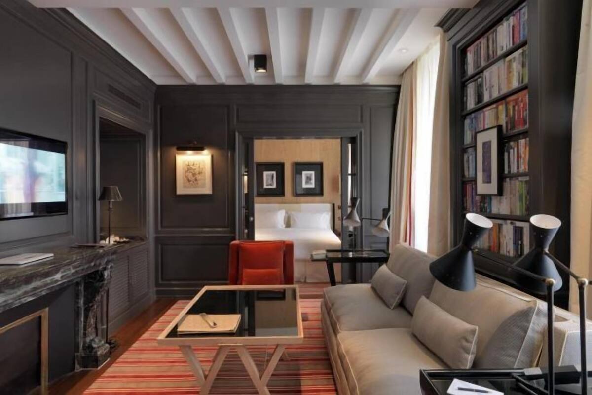 Une chambre d’hôtel moderne équipée d’un canapé, d’une petite table, d’une télévision, d’une bibliothèque et d’une cheminée.