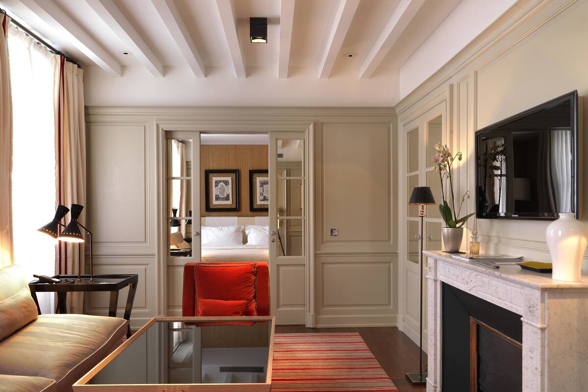 Une chambre d’hôtel comprenant un lit, un canapé, une table basse, une cheminée et un téléviseur.