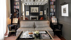 A modern living room with a sofa, coffee table, and bookshelves. - Marquis Faubourg Saint Honoré - Small Luxury hotels of the World (Paris)